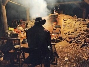 炭焼き窯の前に座っている人の写真