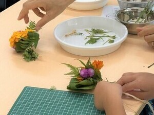草花で花飾りを作っている写真